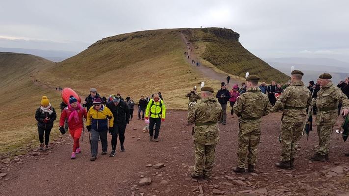 A group of people taking part in one of the many charity events held in the Brecon Beacons - just about to summit Pen y Fan with Corn Ddu in the background