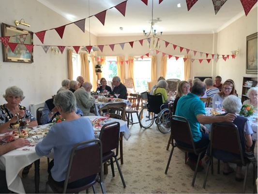Residents enjoying afternoon tea with friends and family in the dining room